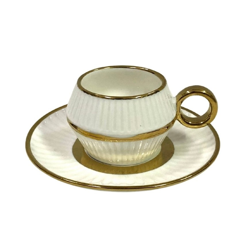 White ceramic cup with gold trim and handle on a matching saucer