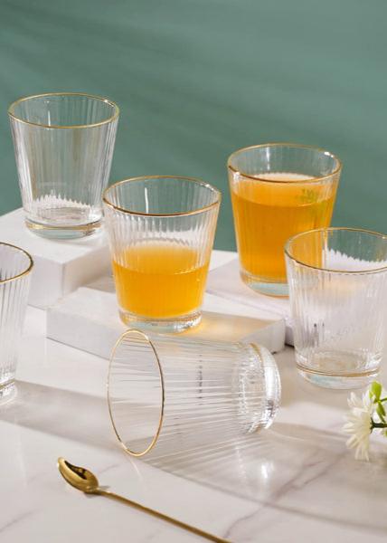 Six short glasses with ribbed texture and gold rims