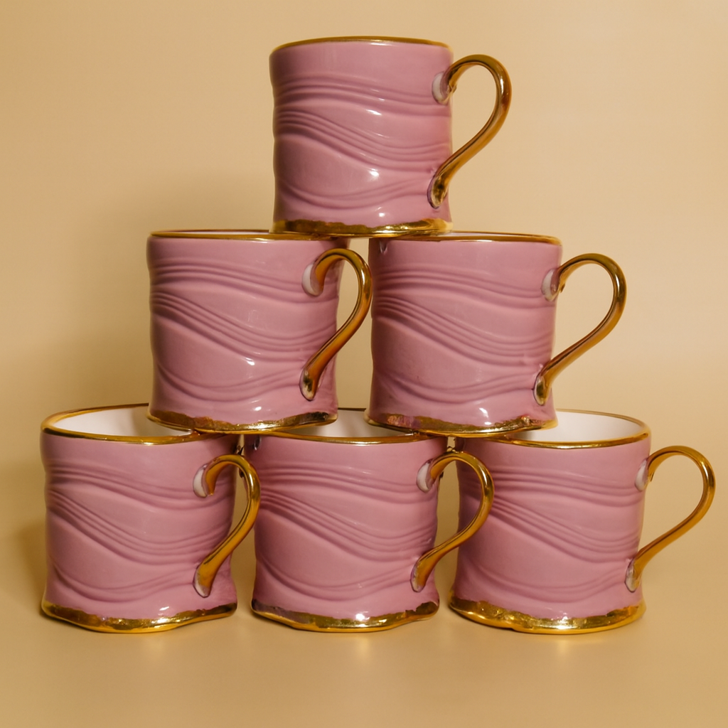 A stack of six mugs with gold handles and rims