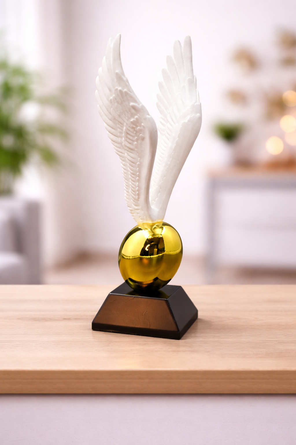 Decorative object with white feathers and a gold sphere on a wooden surface