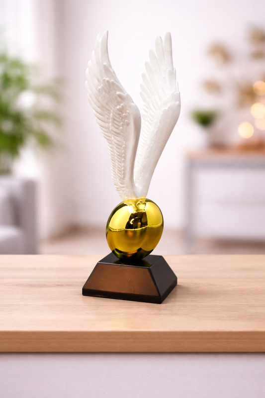 Decorative object with white feathers and a gold sphere on a wooden surface